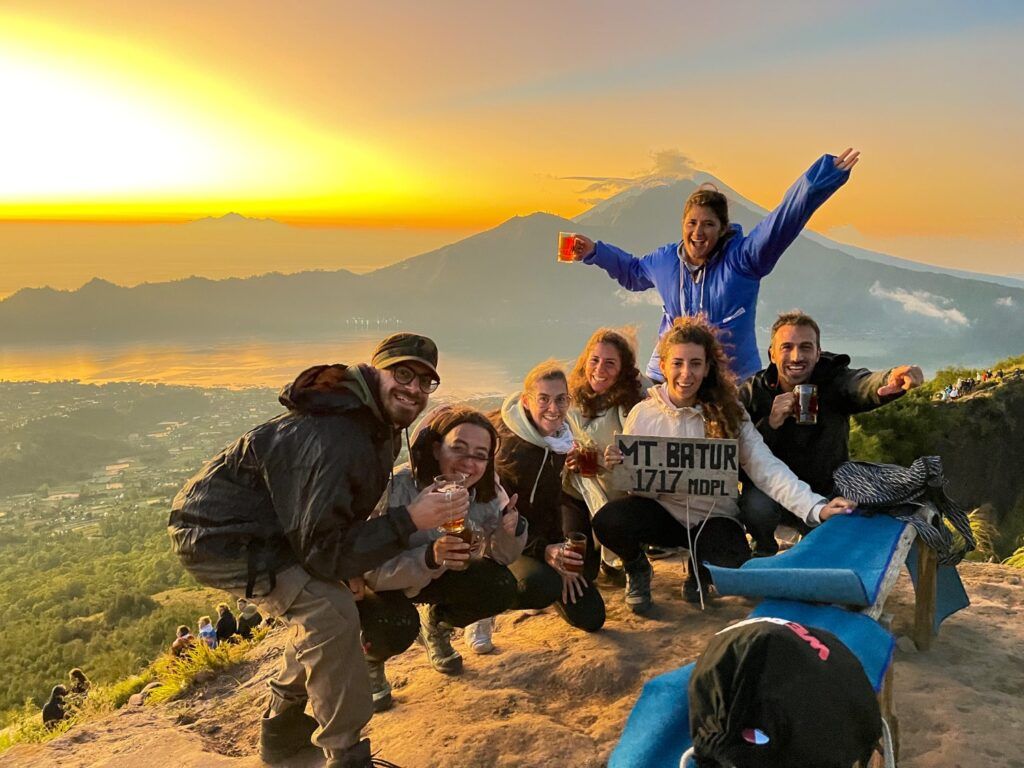 Group posing on Mount Batur summit in Bali at sunrise.