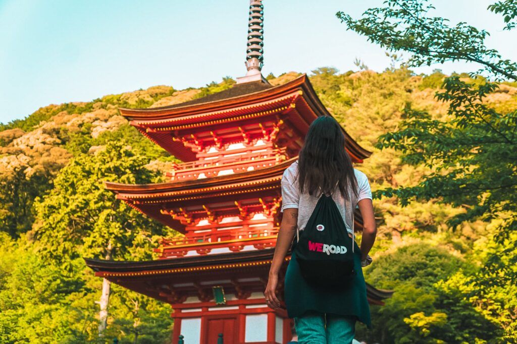 Traveler looking at a red Japanese pagoda near Kyoto.