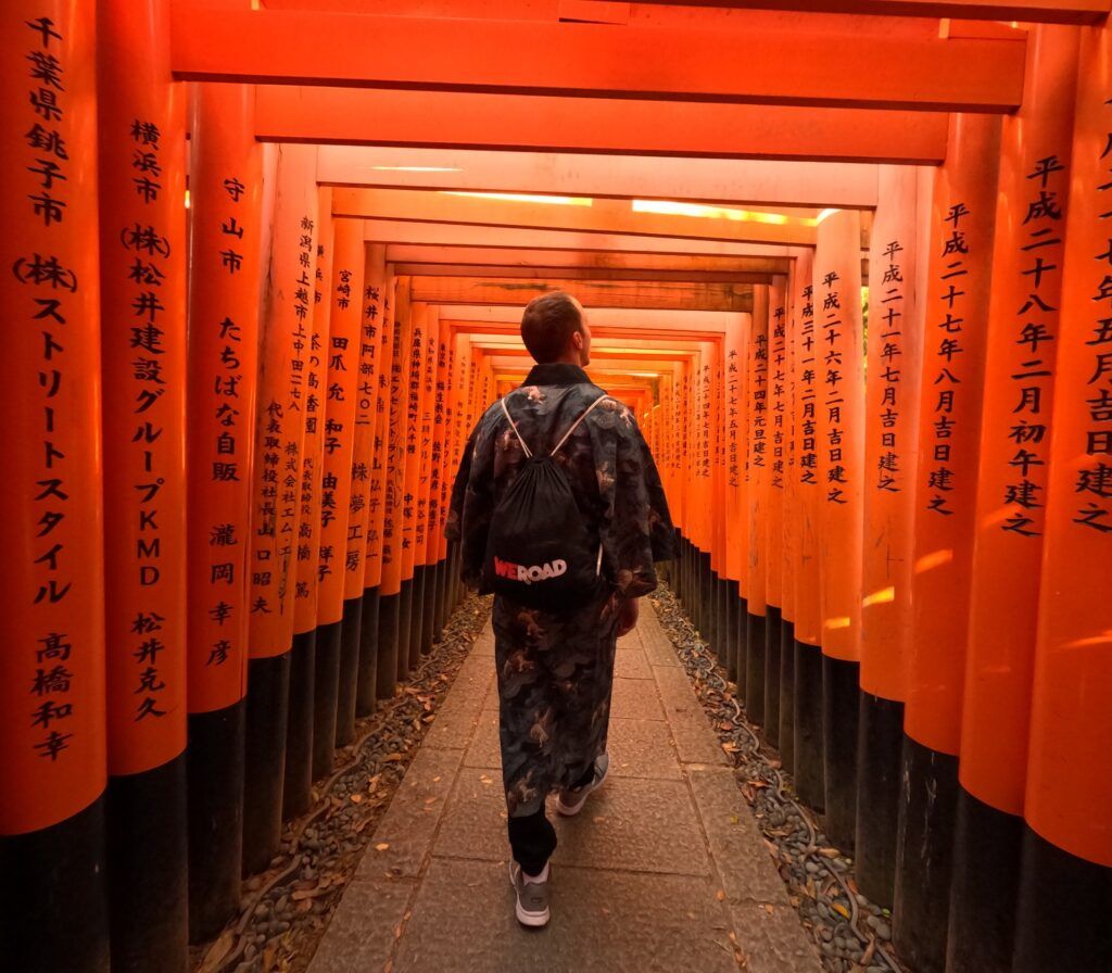 Traveler walking through the thousands of orange torii gates at Fushimi Inari-taisha.