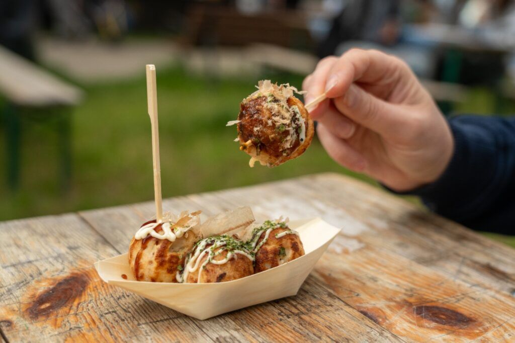 A hand picking up Takoyaki (octopus balls).