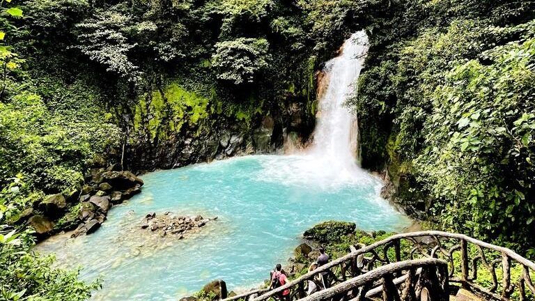 Beautiful turquoise waterfall and pool surrounded by lush green rainforest.