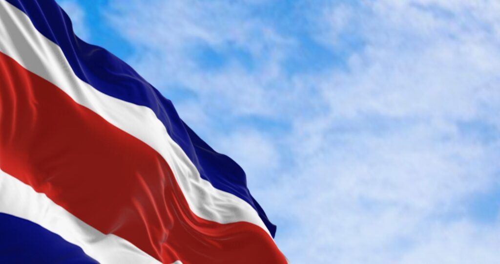 Costa Rica flag waving in the wind against a blue sky with white clouds.
